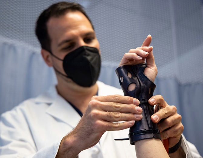 Doctor applying a 3D printed cast from Dimension Ortho to a patient's wrist